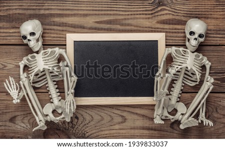 Chalk board with skeletons on wooden table