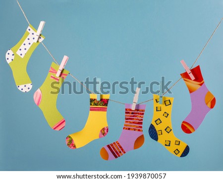 World Down Syndrome Day concept. Different socks in clothesline on blue background. Paper craft.