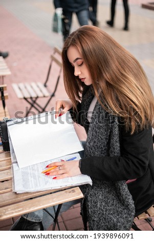 Small busy business owner elegant pretty woman office manager freelancer sitting outside street cafe coffee shop wooden table, signing documents, working with papers. Female entrepreneur, copy space
