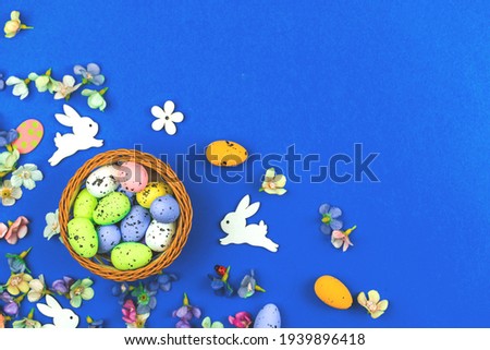 Easter nest with painted colorful eggs and festive bunny on blue background