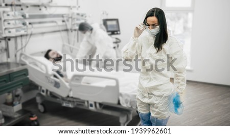 Coronavirus covid-19 infected patient in a quarantine ward at the hospital with doctors in protective suits while they making disease treatment of him