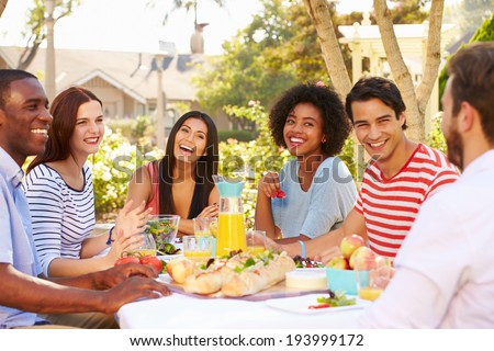 Group Of Friends Enjoying Meal At Outdoor Party In Back Yard Royalty-Free Stock Photo #193999172