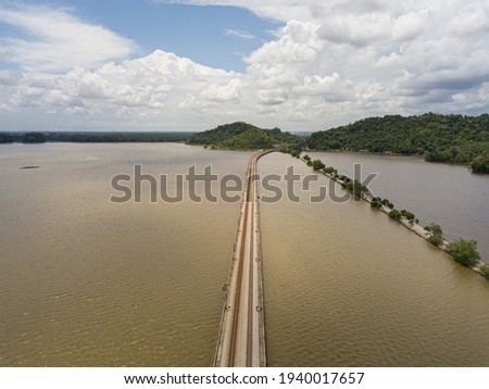 Drone shot from high angle of a railway track bridge across a brown water lake at Bukit Merah, Perak, Malaysia.