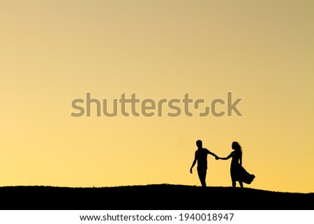 Silhouette couple walking hand in hand at sunset
