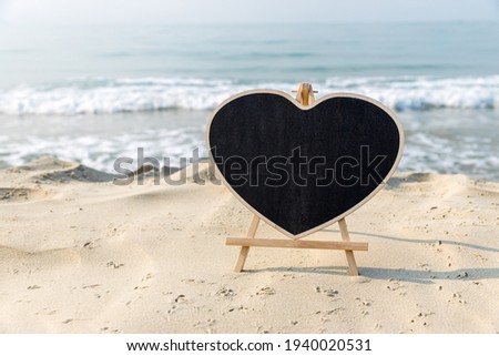 Chalkboard heart shape with a wooden frame Blank Chalk board  heart shape for write text, message or advertising, placed on the sand of a beach. Empty blackboard on sandy beach.