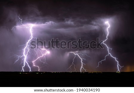 Lightning streak from a thunderstorm cloud at night in a rural setting. There are multiple lightning strikes coming from the thunderstorm. Royalty-Free Stock Photo #1940034190