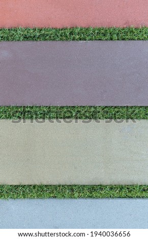 Multi-colored paving slabs. Joints are filled with green grass. Colors - Rosy Brown, Topaz Hue Violet, Tasman Hue Gray, Echo Blue.  