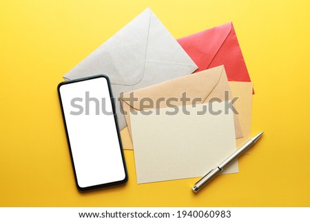 Close up mobile phone with blank screen with envelop and postcard on desk, top view