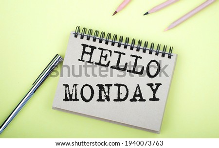 HELLO MONDAY text on notebook with pen on yellow background