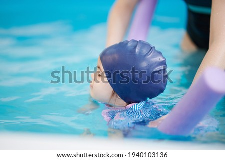 Small kid try to swim in pool blue water background