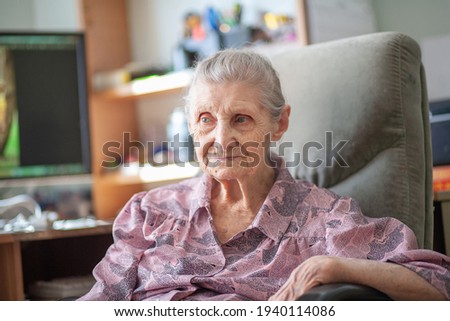 An old pensioner woman sits at home in a chair, a grandmother smiles, the life of the elderly.
