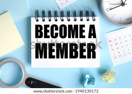 Become a Member. text on white notepad paper on blue background. near stickers, magnifying glass, white keyboard, calendar