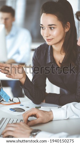 Business woman and man discussing questions while using computer at workplace in modern office. Teamwork, meeting and brainstorming concept