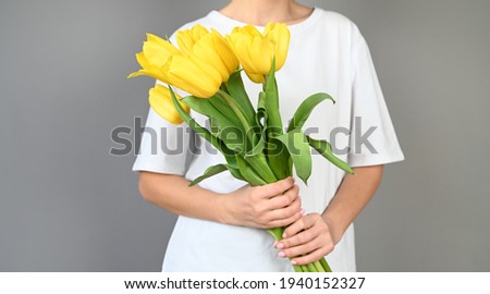 Woman holds tulips in her hands. Florist girl gathered a bouquet. Beautiful yellow flowers. High quality photo