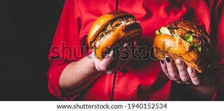woman chef holding two burger in hand