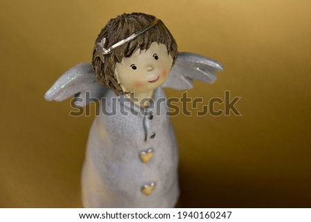 Cute little girl angel statuette stock images. Adorable angel figurine on a golden background with copy space for text. Beautiful ceramic statuette girl angel images photo