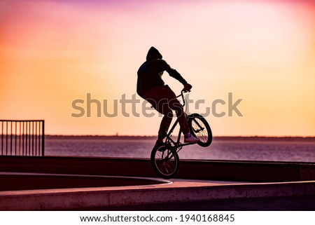 Silhouette of Young man jumping with his BMX Bike at skate park.