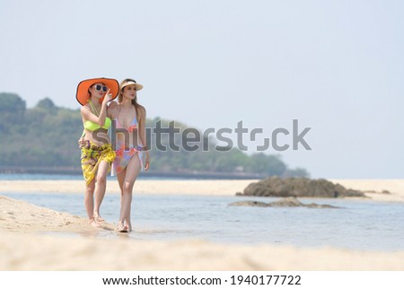 Asian women in bikini walking on the beach ,traveling summer holiday Thailand.