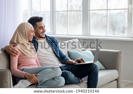 Happy young muslim family using laptop together at home