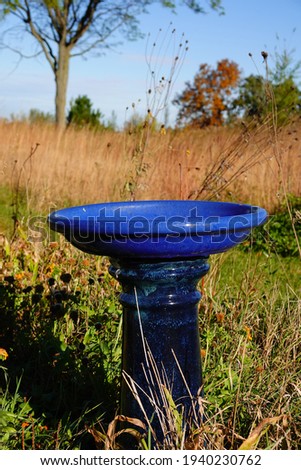 Molded concrete royal blue bird bath sits alone on the countryside during the autumn fall season in Fond du Lac, Wisconsin 