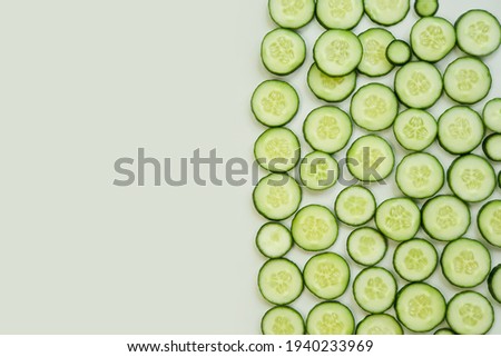 Top view of fresh sliced cucumbers on green background with copy space.