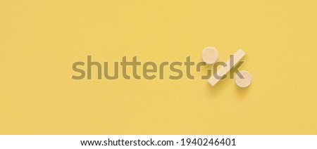 percentage sign with wooden cubes on yellow background, interest rate decline, investment reduce or sales discount concept, copy space