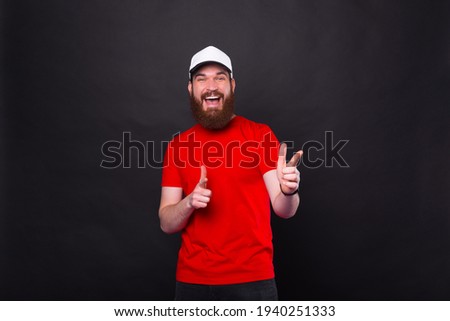 Joyful excited man pointing at you, bearded man point at camera over black background.