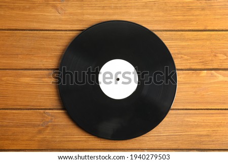 Vintage vinyl record on wooden table, top view