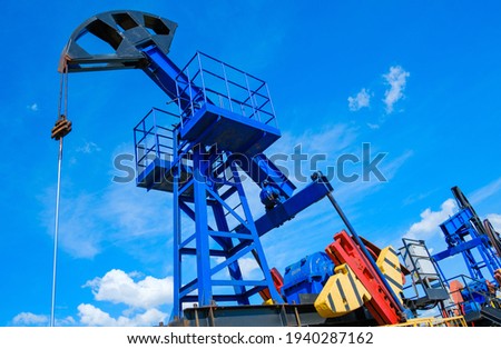 From below industrial machinery pumping oil from wells against cloudy sky on sunny day in countryside