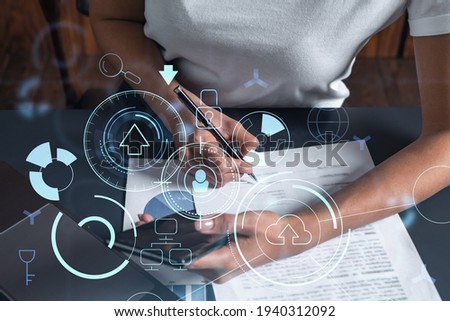 Businesswoman is signing the contract to create a software to present it at start up conference and gain investments for innovative service. Checking the details at smartphone. Hologram tech graphs.