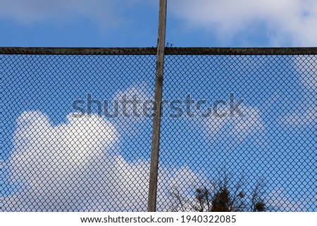 Wire fence against blue sky with white clouds. Protection or freedom concept