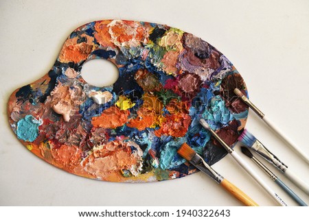 close-up of art palette. bright spots of oil paints. used palette. multi-colored paints. there is room for text. paint brushes