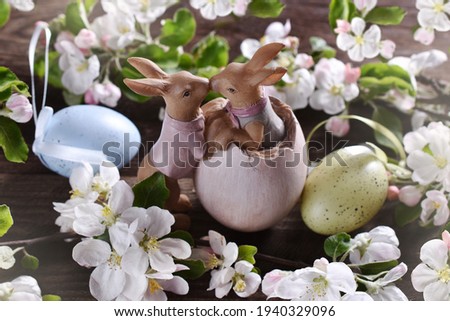 Easter background with cute kissing bunny figurines and spring apple tree blossoms on wooden table