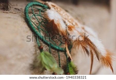 beige and green dream catchers  (dream hunter) with feathers on a stone background