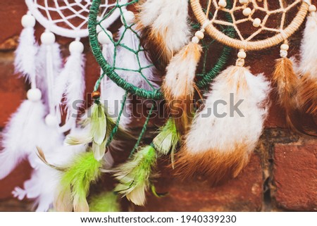 
white, beige and green dream catchers  (dream hunter) with feathers on a brick background