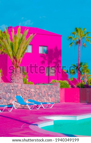 Fashion tropical minimal location. Pink Hotel, swimming pool and Palm. Blue Summer sky. Canary islands.  Travel aesthetics wallpaper