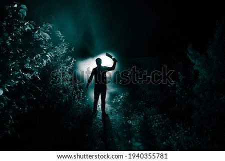 Silhouette of killer with knife standing in the dark forest with light. Horror halloween concept. strange silhouette in a dark spooky forest at night