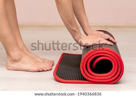 Close-up in the gym. Hands unroll the carpet. Exercise fitness. Healthy lifestyle.