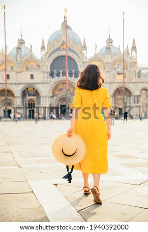 woman in yellow sundress with straw hat walking to saint mark basilica venice italy