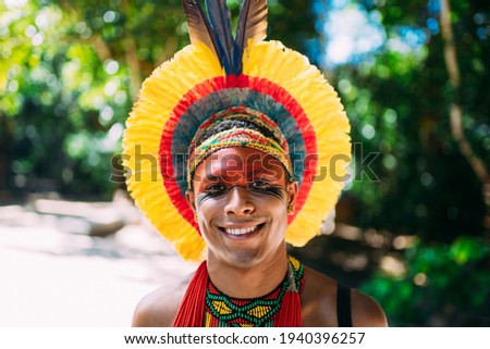 Indian from the Pataxó tribe with feather headdress looking at the camera. Indigenous man from Brazil, with traditional face paintings Royalty-Free Stock Photo #1940396257