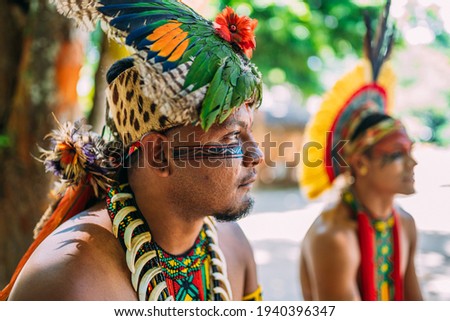 Chief of the Pataxó tribe. Brazilian Indian with feather headdress, necklace and traditional facial paintings looking to the right Royalty-Free Stock Photo #1940396347