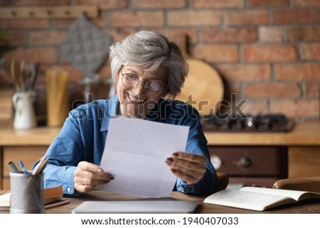 Happy retired hispanic woman bank client hold official document notification informing loan mortgage is paid. Glad smiling aged latin lady read paper letter received by mail satisfied with good news Royalty-Free Stock Photo #1940407033