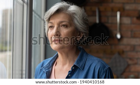 Retirement problems. Worried depressed old age latin lady stand by window look away troubled with bad health loneliness. Upset mature hispanic grandma miss children husband lost in sad heavy thoughts Royalty-Free Stock Photo #1940410168