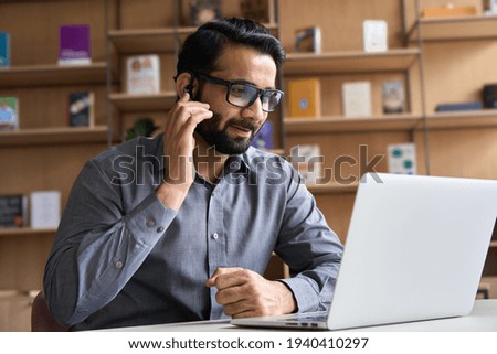 Indian business man professional employee, remote consultant, customer service support manager wearing headset talking at virtual meeting consulting client on video call at home office call center. Royalty-Free Stock Photo #1940410297