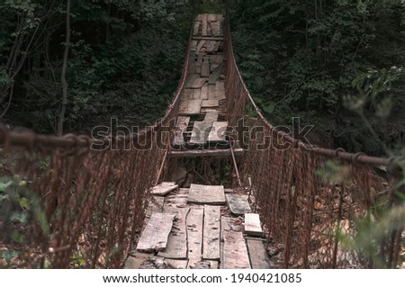 Destroyed suspension bridge over a mountain river (concept: dangerous path) Royalty-Free Stock Photo #1940421085