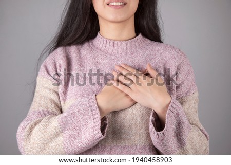 happy woman hand in heart on grey background