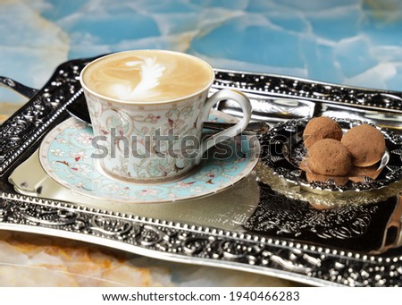 a cup of cappuccino with cakes on a tray
