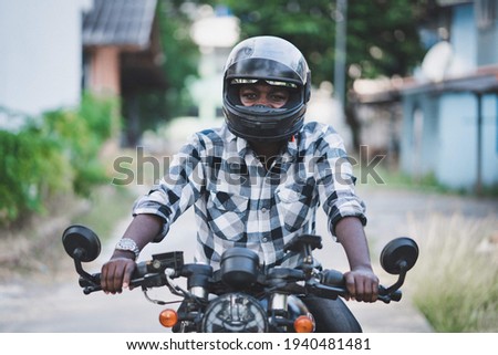 A smiling motorist riding a motorcycle and having fun . 
