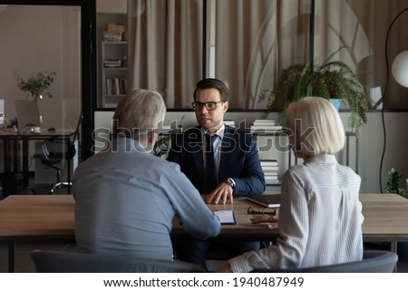 Male Caucasian specialist have meeting with mature couple clients, discuss health insurance for older people. Middle-aged spouses customers consult with relator or broker. Realty, rent concept. Royalty-Free Stock Photo #1940487949