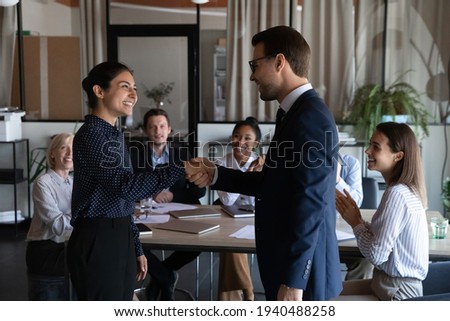 Smiling diverse multiracial employees handshake close deal agreement at meeting. Happy multiethnic businesspeople shake hand get acquainted greet at briefing, congratulate colleague with promotion.